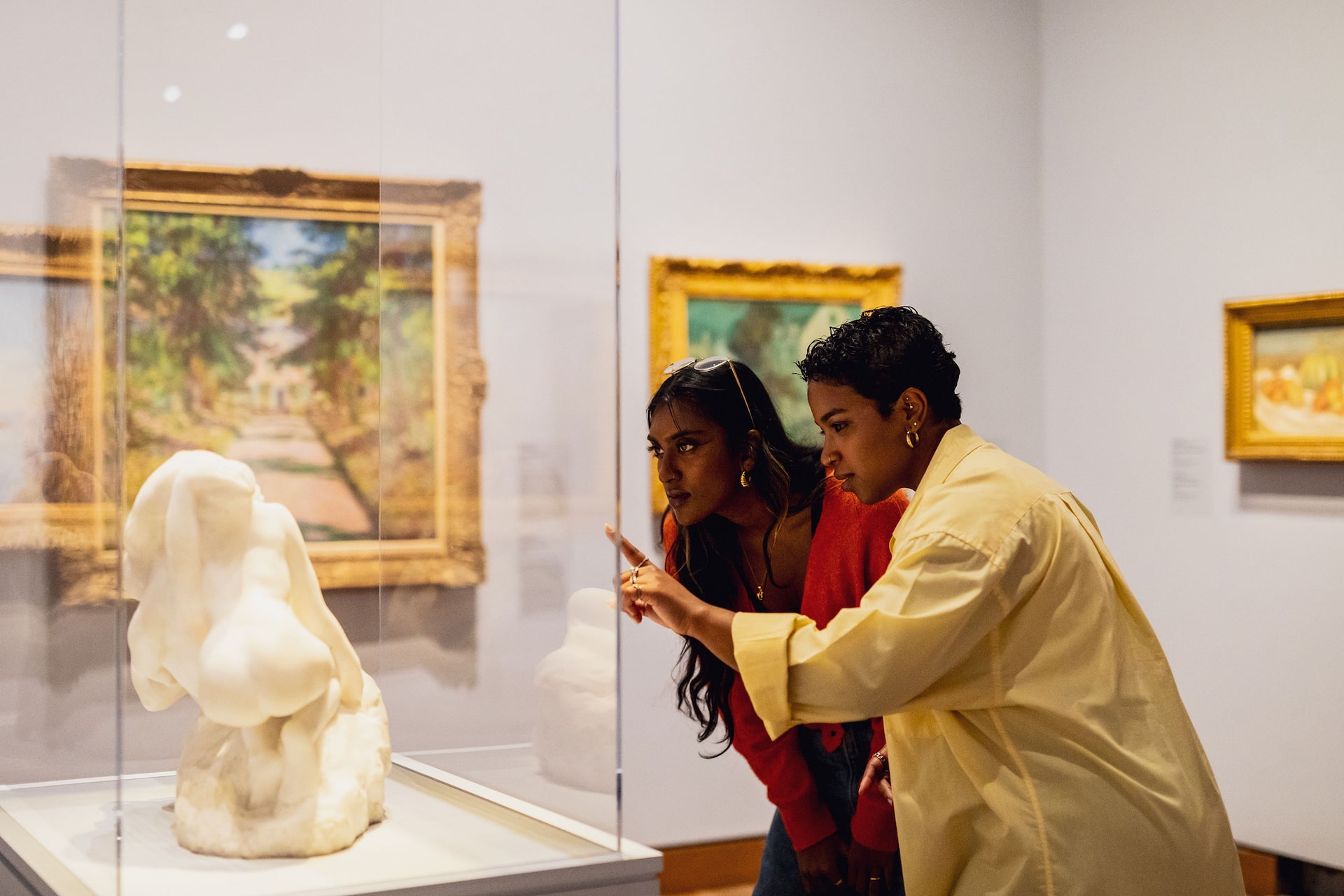 deux jeunes femmes regardant une sculpture dans un mus&eacute;e