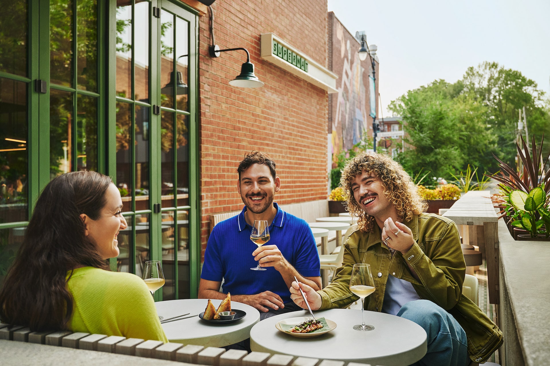 trois jeunes buvant un verre &agrave; table en terrasse &agrave; Montr&eacute;al